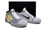 Pair of white and black basketball shoes shown with a dark box behind them.