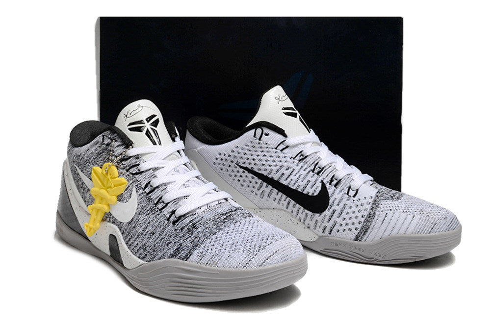 Pair of white and black basketball shoes shown with a dark box behind them.
