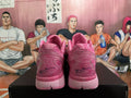 Rear view of a pair of pink Nike basketball sneakers showing the padded collars, heel details, and black heel signatures.