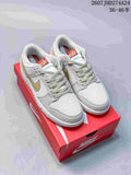 Pair of white and light gold Nike SB Dunk Low Pro sneakers displayed on a red shoebox.