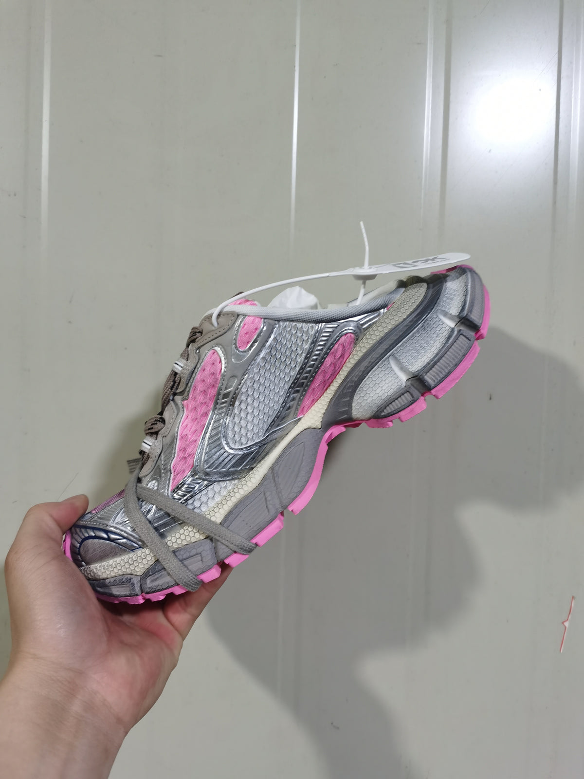 Side view of the grey and pink sneaker showing textured panels, grey laces, and the pink outsole.