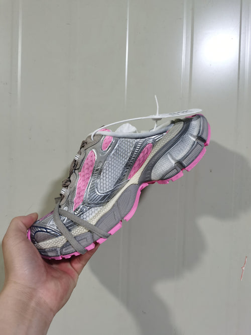 Side view of the grey and pink sneaker showing textured panels, grey laces, and the pink outsole.