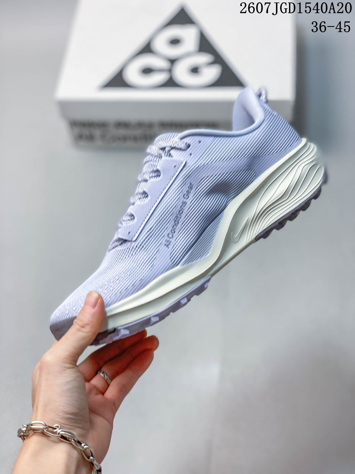 Side profile of the light lavender sneaker showing the gray Swoosh, textured upper, lace-up construction, and sculpted cream-colored midsole.