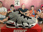 Side view showing the grey sculpted upper, red accents, black detailing, and visible sole cushioning