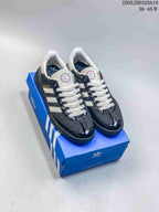 Pair of black and white Adidas Originals low-top sneakers displayed on a blue Adidas shoebox.