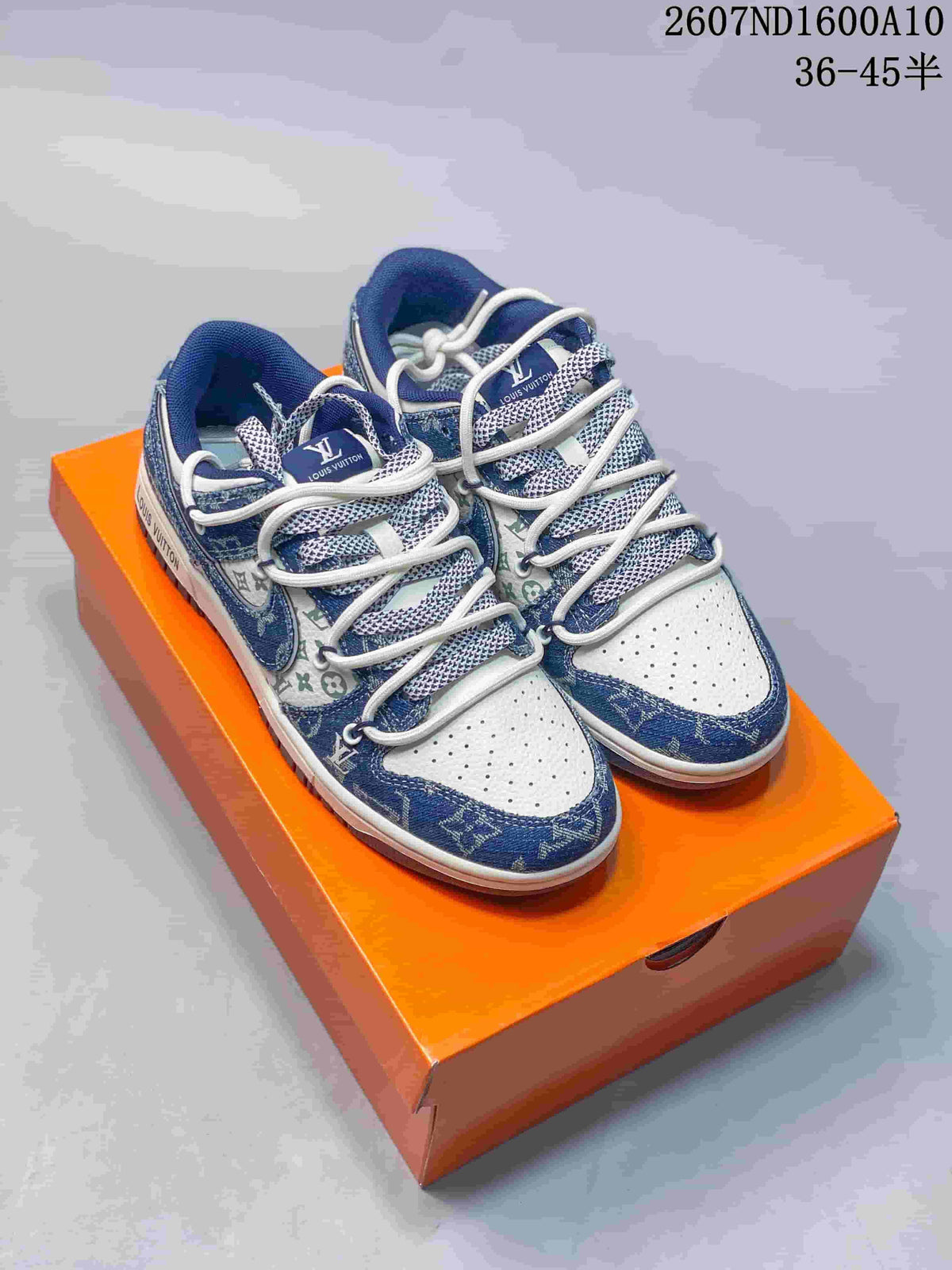 Pair of blue and white low-top sneakers displayed on an orange box, with patterned panels and white laces visible.