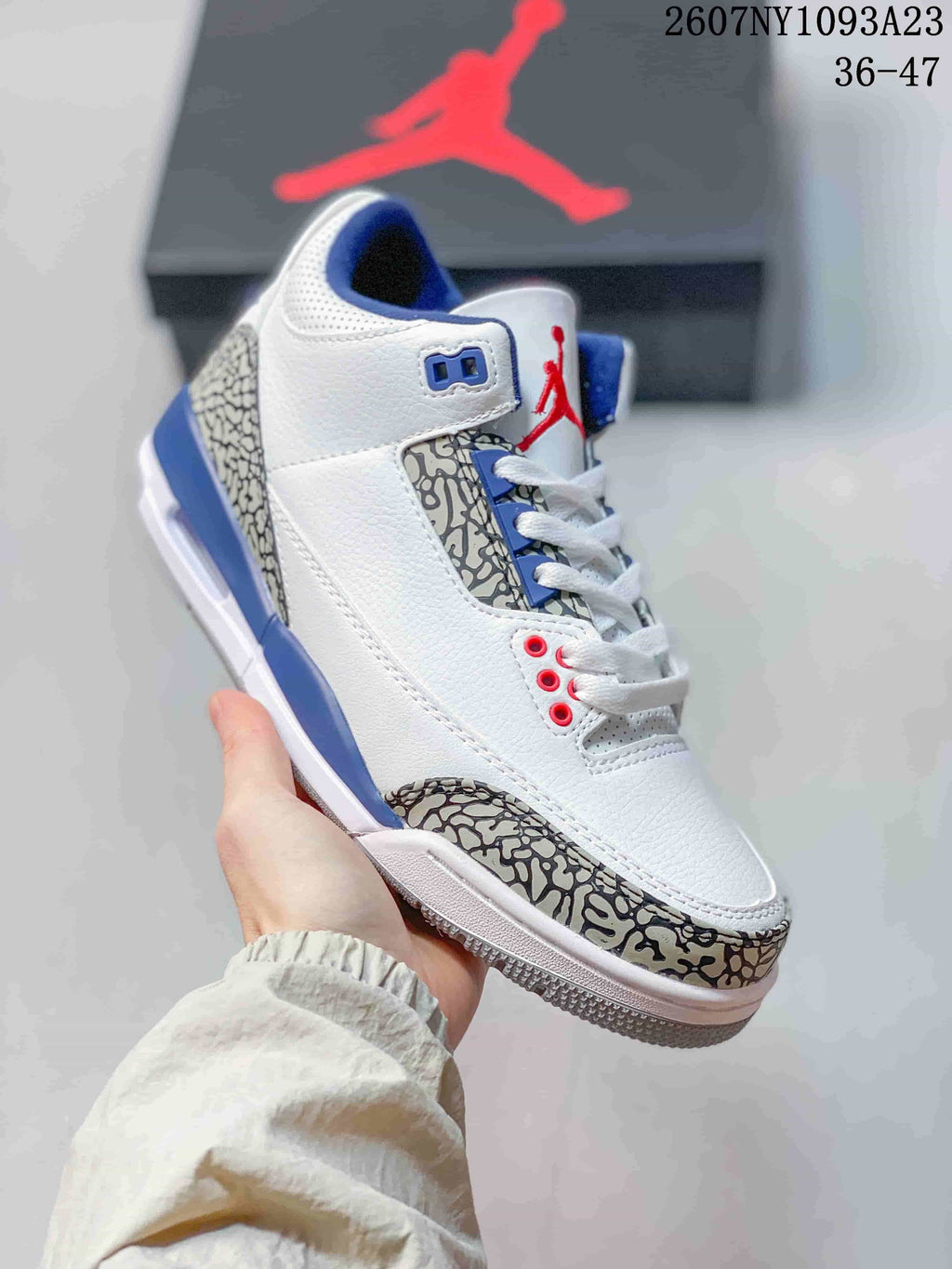 Angled side view of the white high-top sneaker with blue accents, red details, and elephant-print overlays.