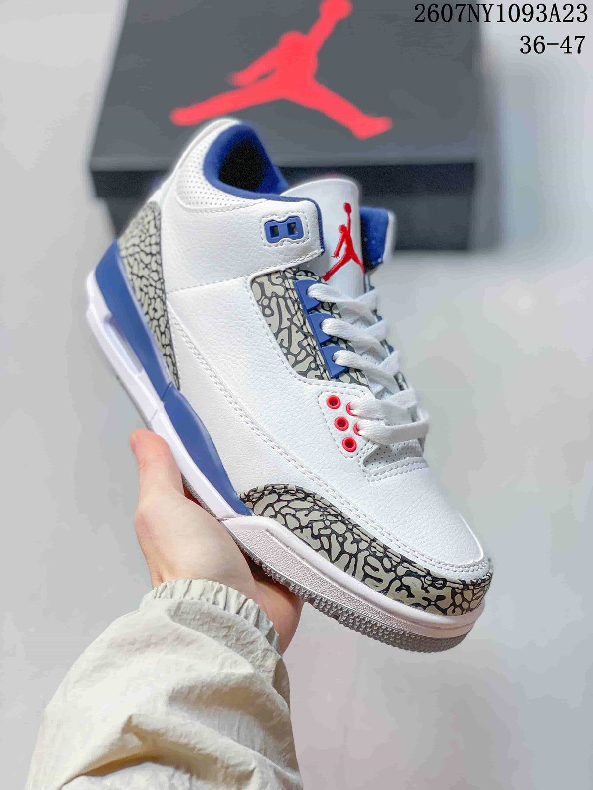 Angled side view of the white high-top sneaker with blue accents, red details, and elephant-print overlays.