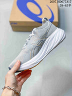 Side view of the gray ASICS running sneaker showing the layered textile upper, logo detailing, laces, and sculpted midsole.