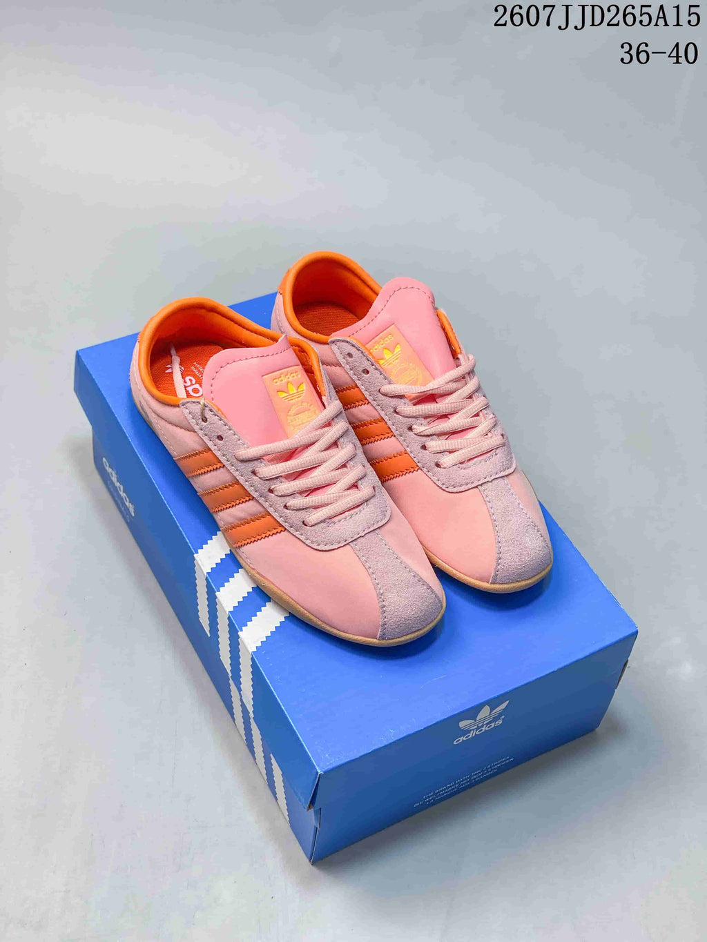 Pair of pink and orange adidas Tokyo low-top sneakers displayed on a blue adidas shoe box.