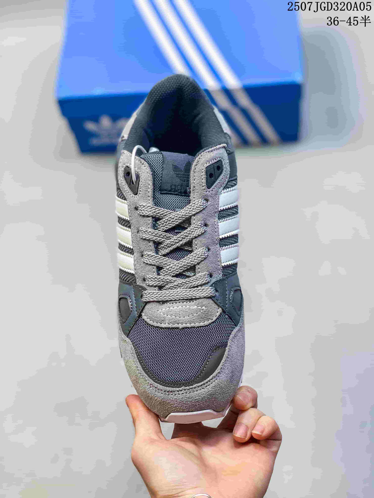 Front view of a grey adidas ZX 750 sneaker with grey laces and white stripes.