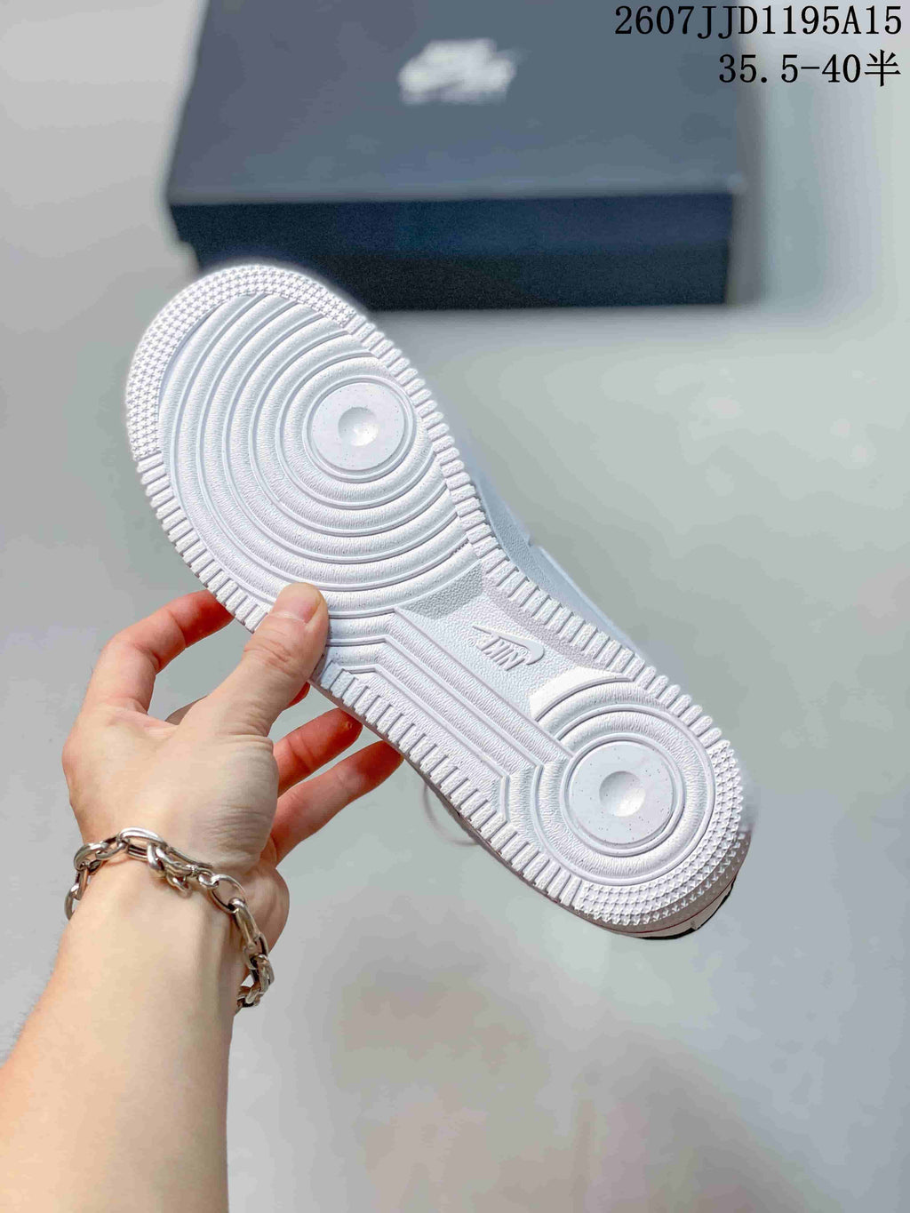 Underside of a white sneaker showing the textured rubber outsole and circular traction pattern.