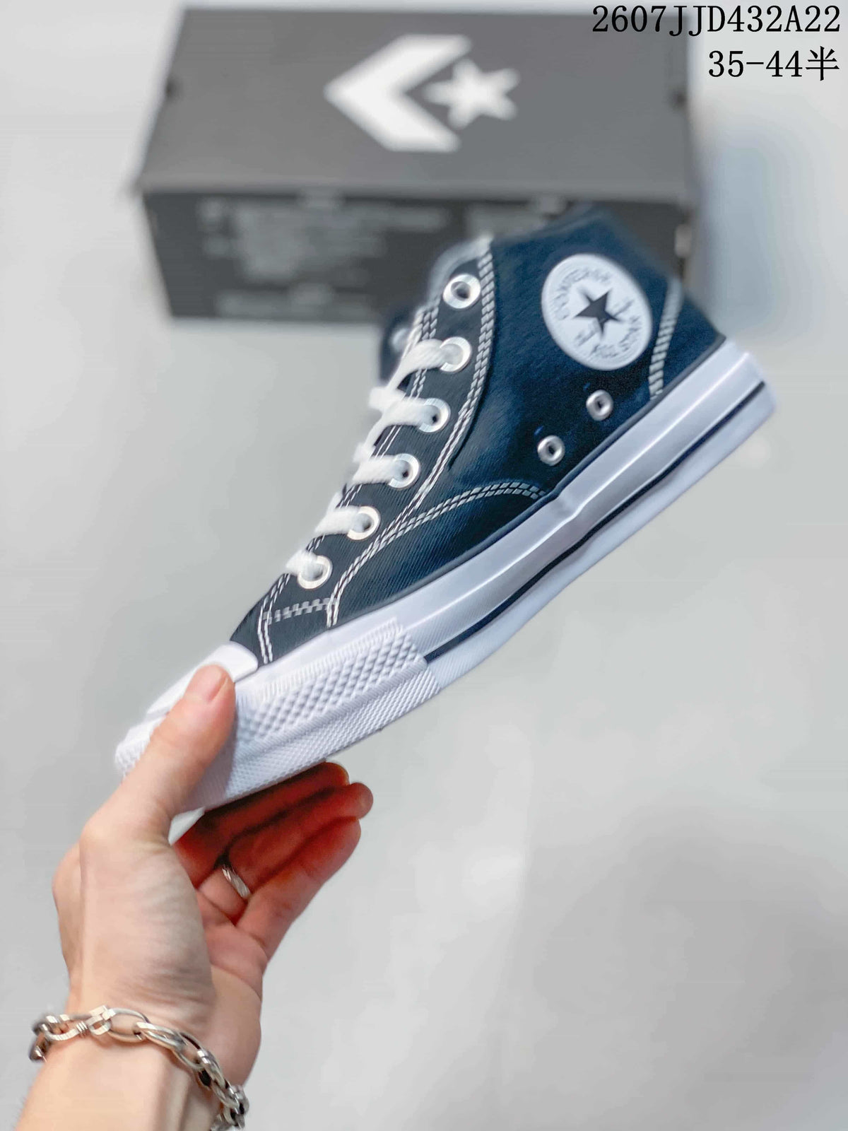 Side view showing the navy canvas upper, metal eyelets, white laces, ankle patch and rubber sole.