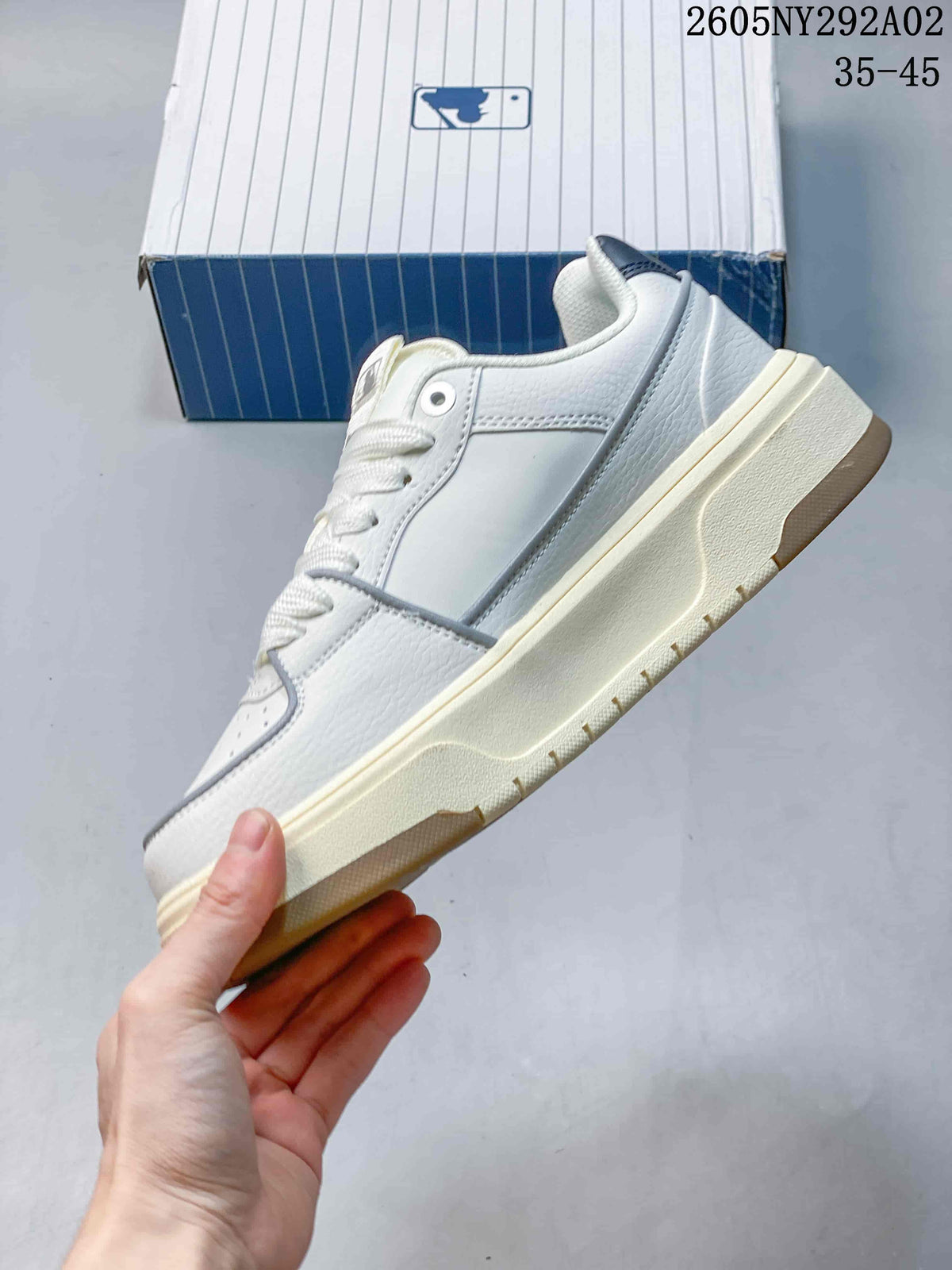 Side view of the white and cream low-top sneaker showing layered panels, contrast trim, and a chunky cream sole.