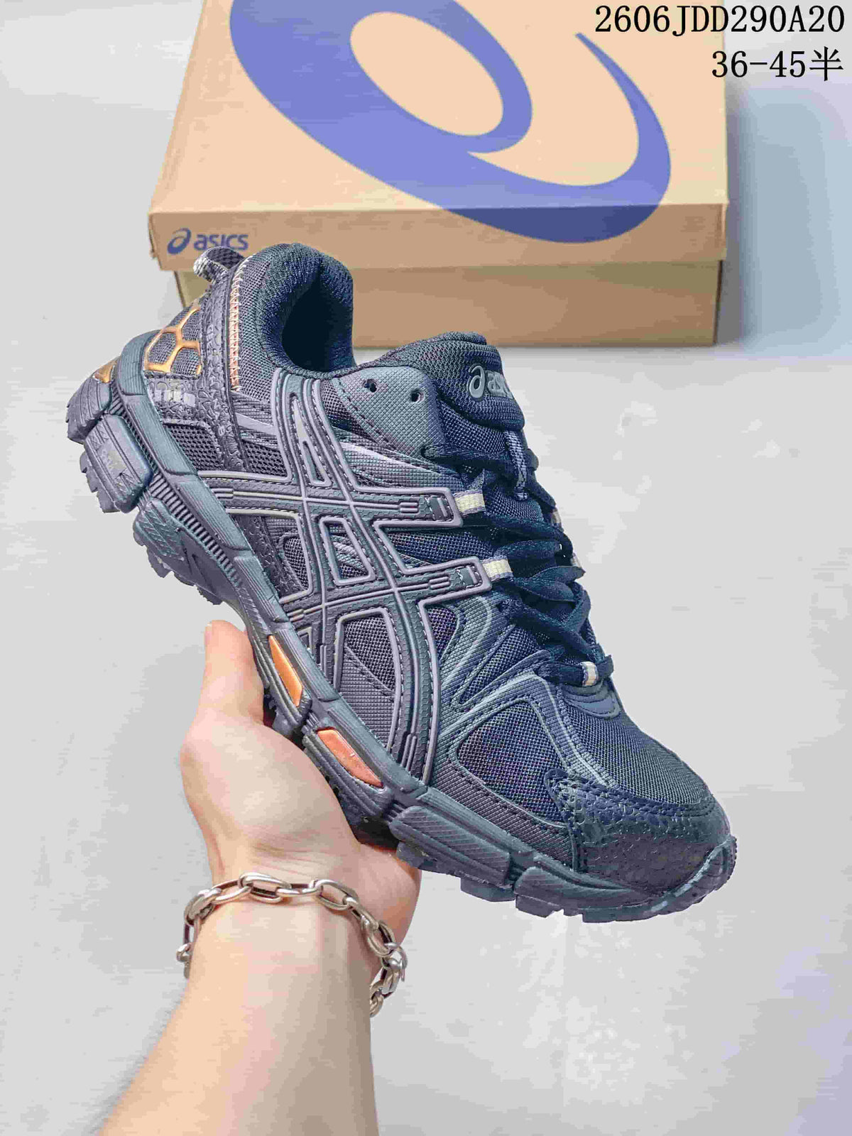 Dark navy and grey ASICS Gel-Kahana 8 sneaker held in front of a shoebox
