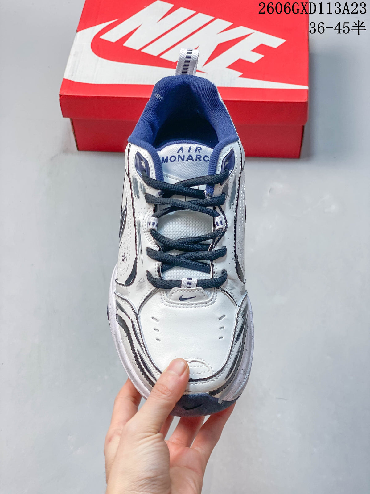 Top view of a white Nike Air Monarch IV sneaker with navy laces and collar lining.