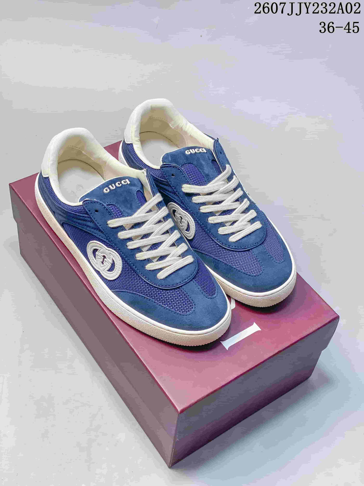 Pair of blue low-top sneakers with white laces and soles, shown on a branded box
