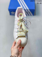 Top view of the sneaker showing the shell-style toe cap, layered pastel laces, and decorative bead accents.