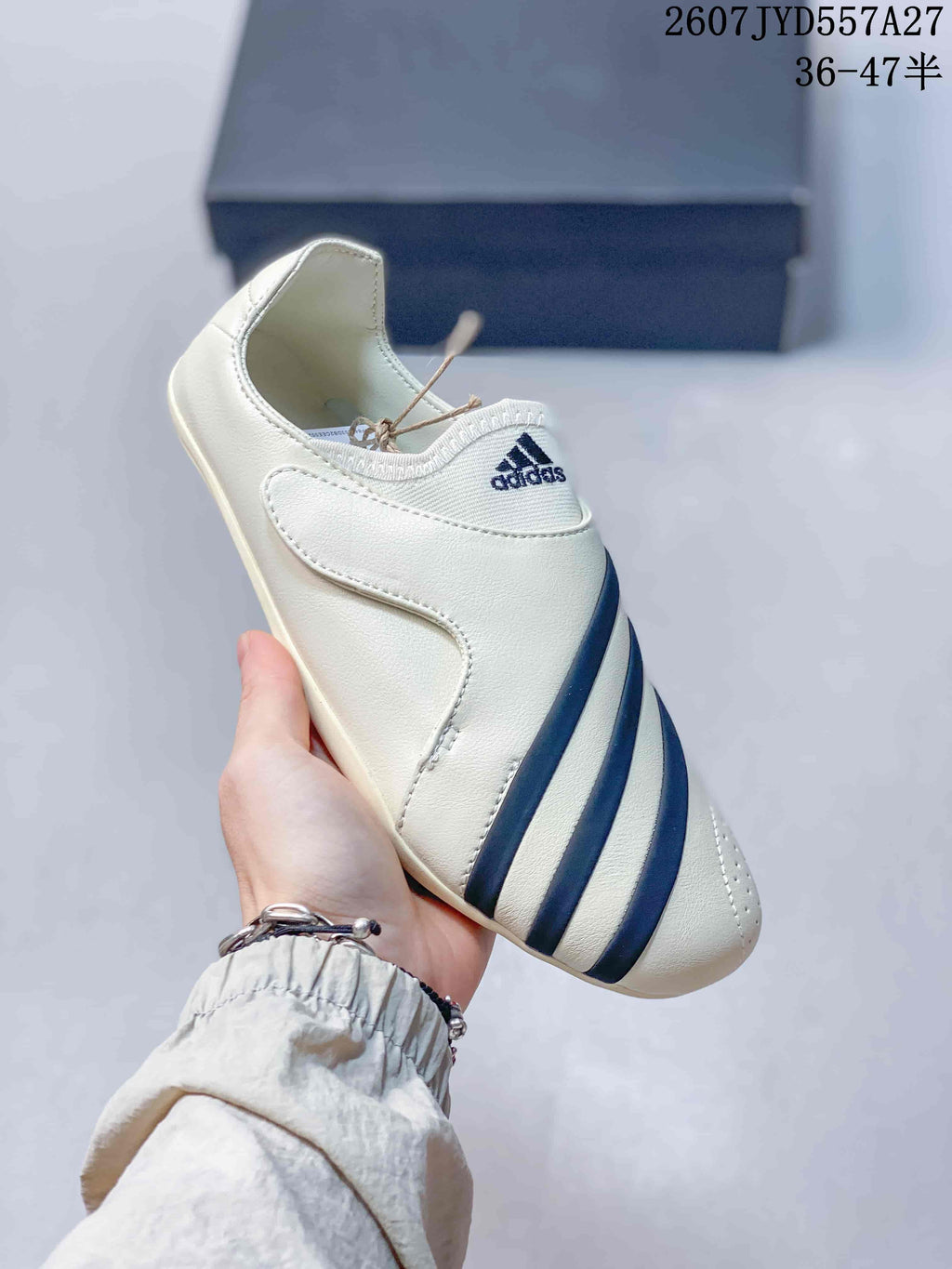 Angled side view of the off-white sneaker showing its low-profile slip-on-style upper and navy stripes.