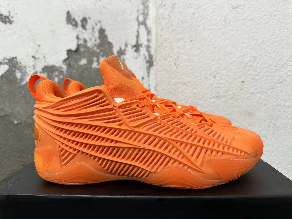 Side view highlighting the sculpted cage-style panels on orange Adidas basketball sneakers.