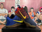 Pair of navy and red basketball shoes with yellow Swoosh details, shown from the side.