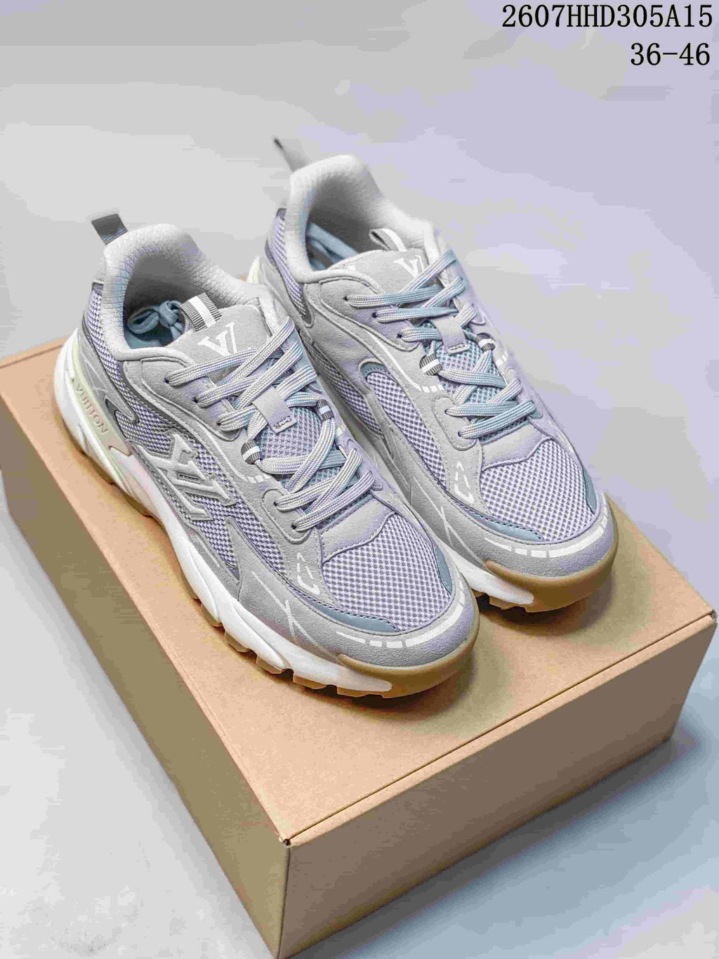 Pair of gray Louis Vuitton sneakers displayed on a shoebox, showing mesh panels, layered overlays, and tan outsole edges.