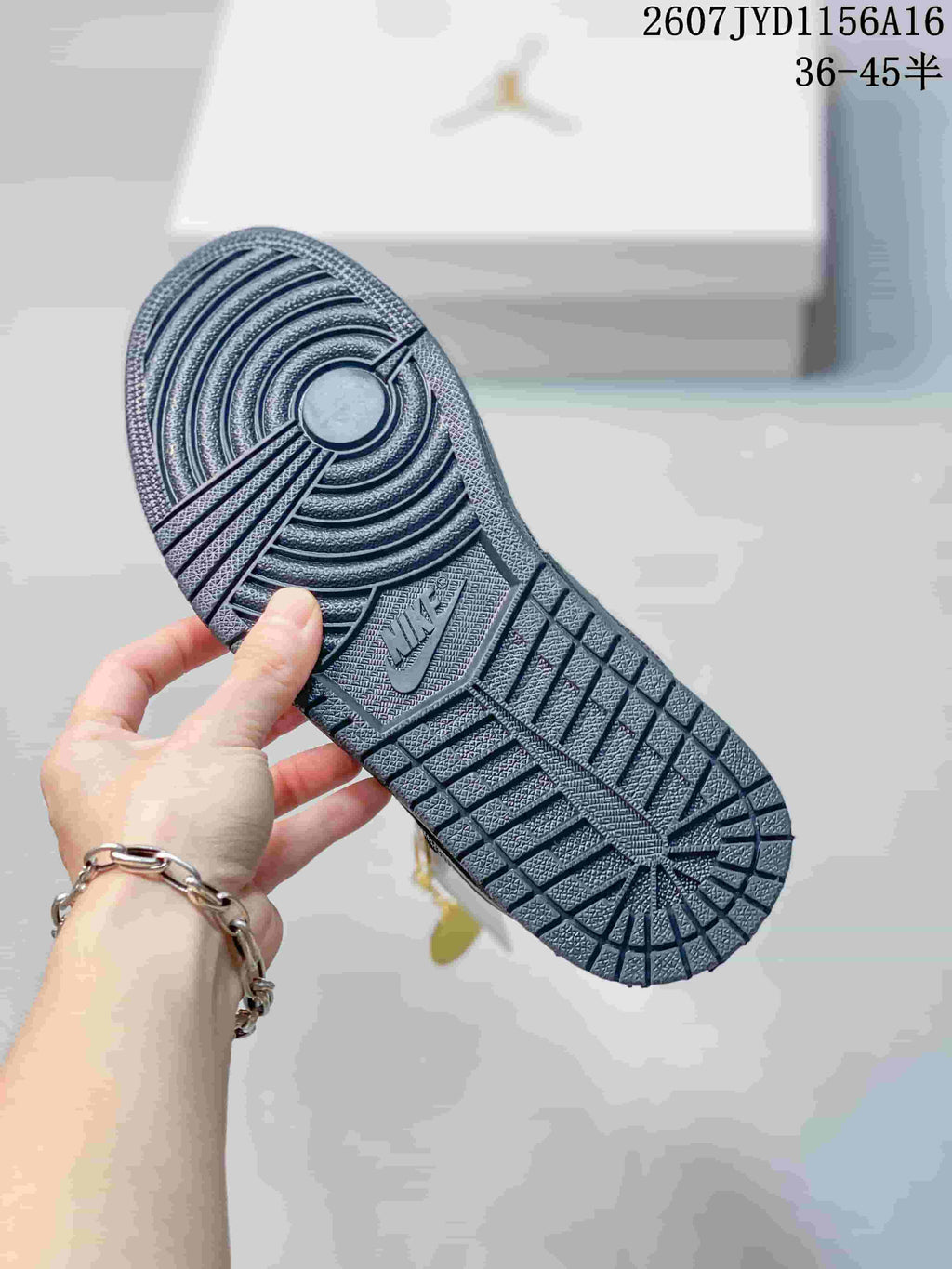 Underside view of a black sneaker showing the circular and geometric rubber outsole tread.