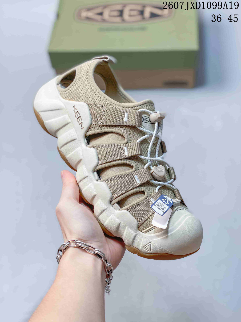 Light beige Keen sandal with white laces, open upper panels, a textured outsole edge and a protective toe bumper; the image includes the size range 36–45.
