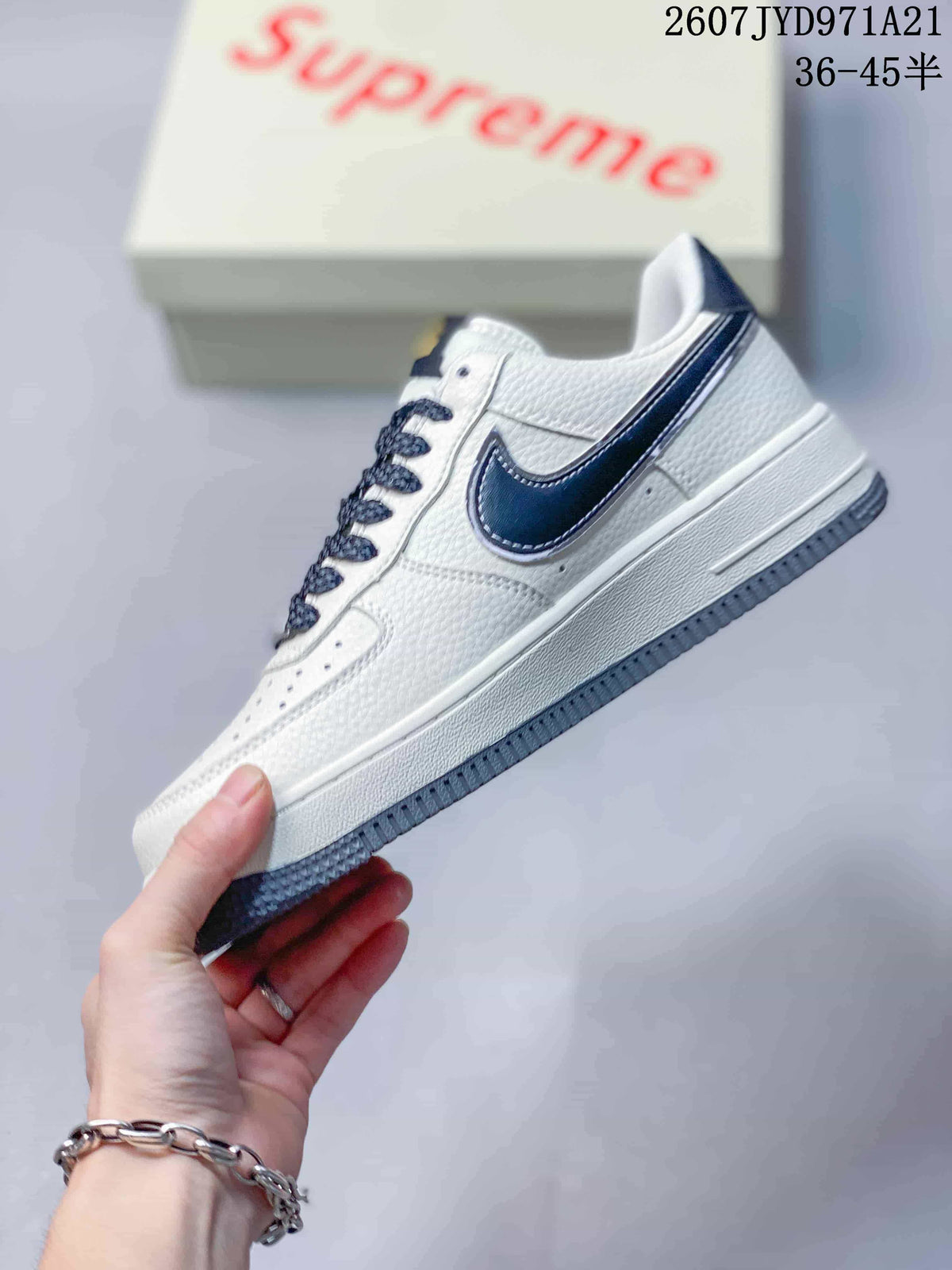 Side profile showing the white low-top construction, navy Swoosh, layered midsole and grey outsole.