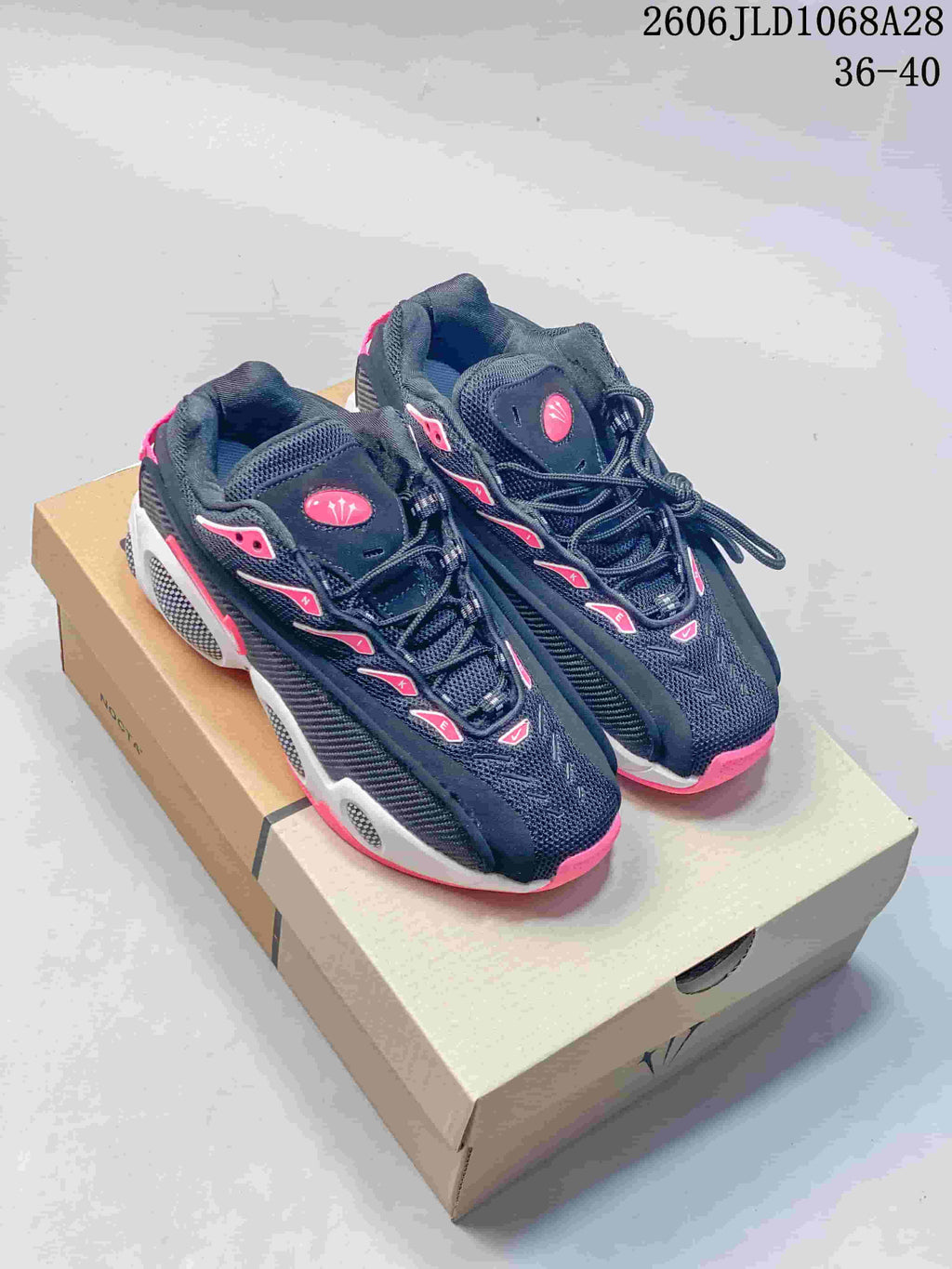Pair of black Nike NOCTA Glide sneakers with white and pink accents, shown on a shoebox
