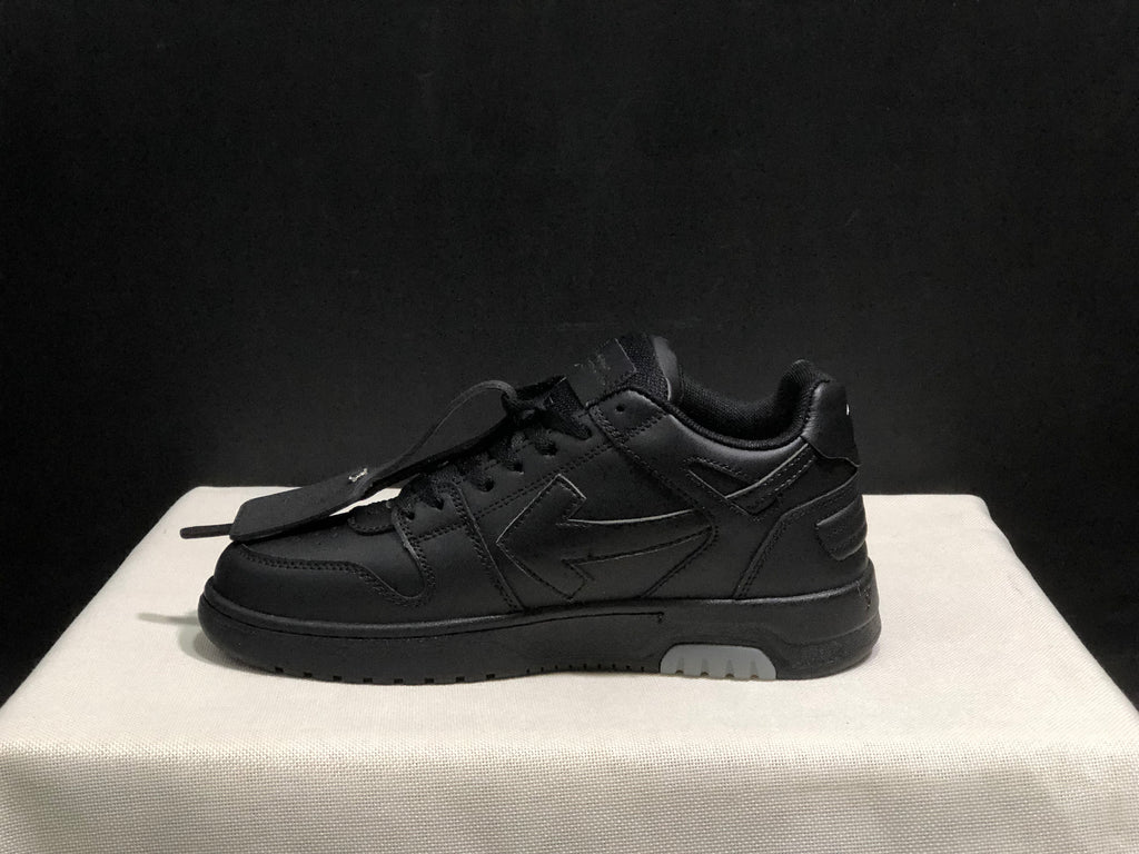 Side profile of a black low-top sneaker showing layered side panels, padded collar and light outsole inserts.