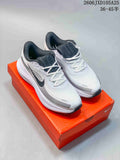White Nike Air Zoom Pegasus running shoes with dark accents, displayed on an orange shoe box.