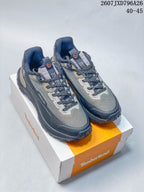 Pair of gray and navy Timberland Motion Access low-top hiking shoes displayed on a Timberland shoebox.