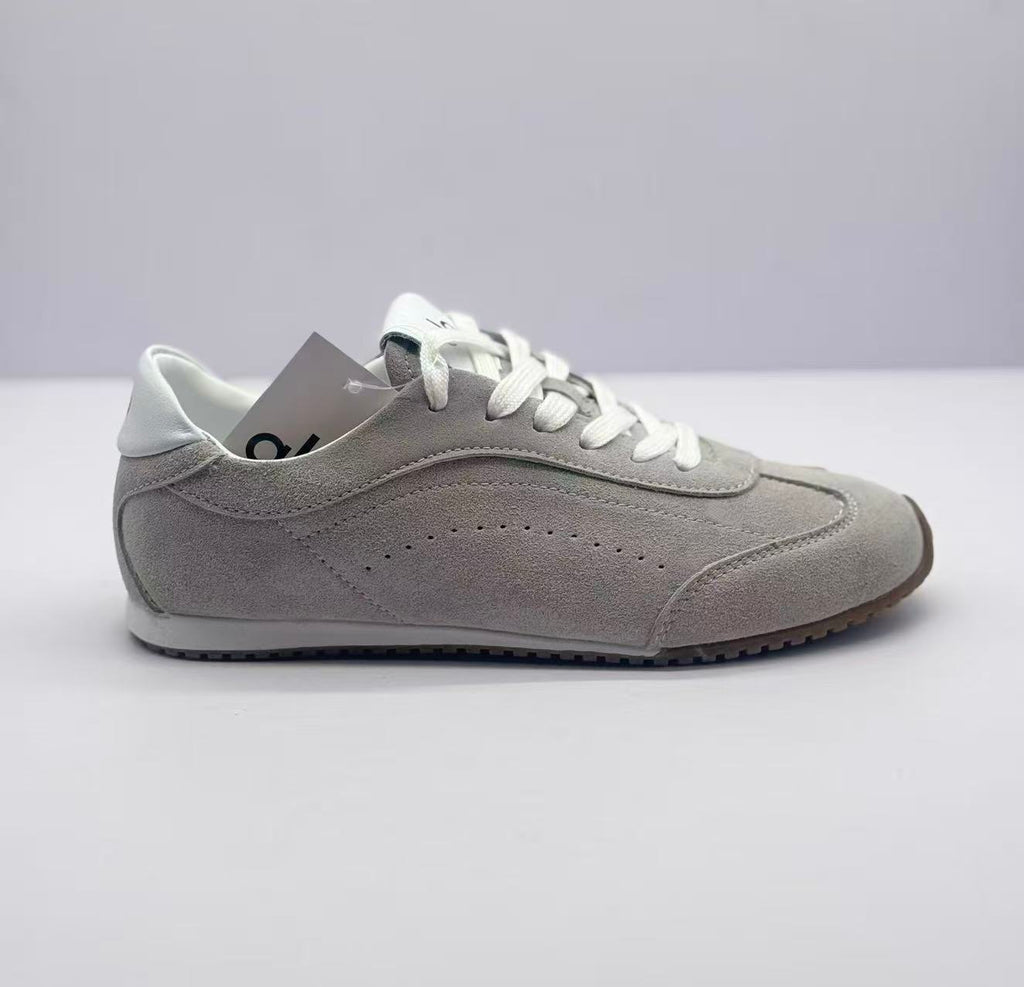 Profile view showing the gray sneaker upper, stitched panels, white heel collar, and low rubber sole.