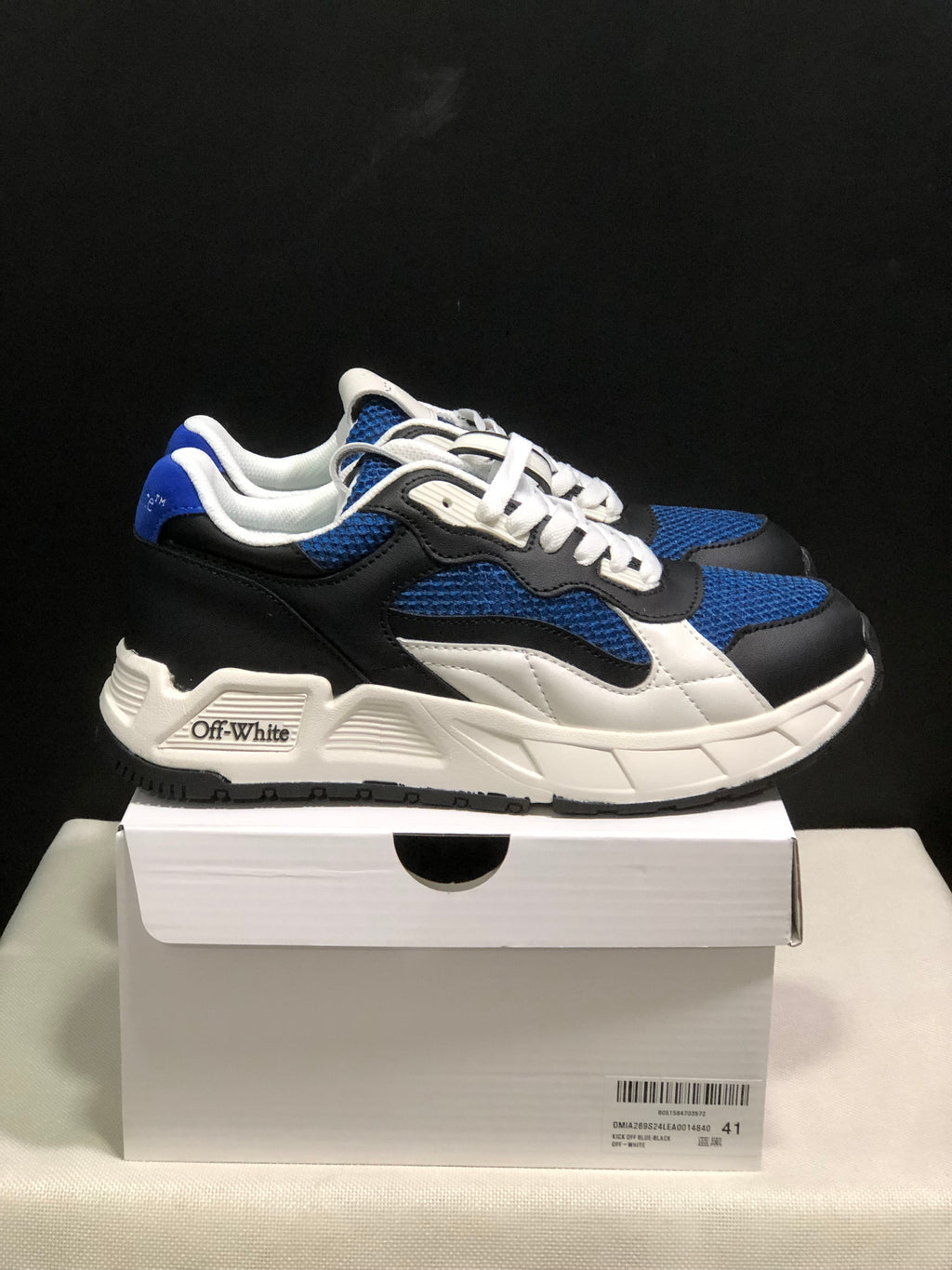 Side profile of a black, blue, and white sneaker pair with white midsoles and Off-White branding on the side.