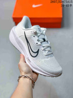 Angled side view showing the white upper, black Swoosh, laces, and patterned outsole.