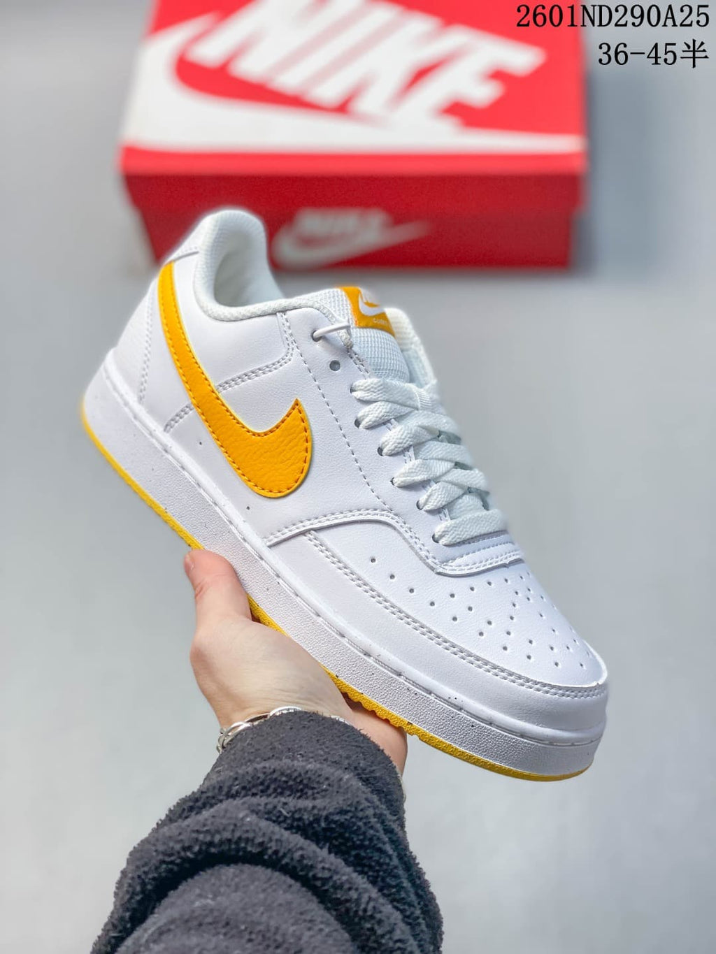White Nike Court Vision Low sneaker with a yellow Swoosh and yellow outsole accents.