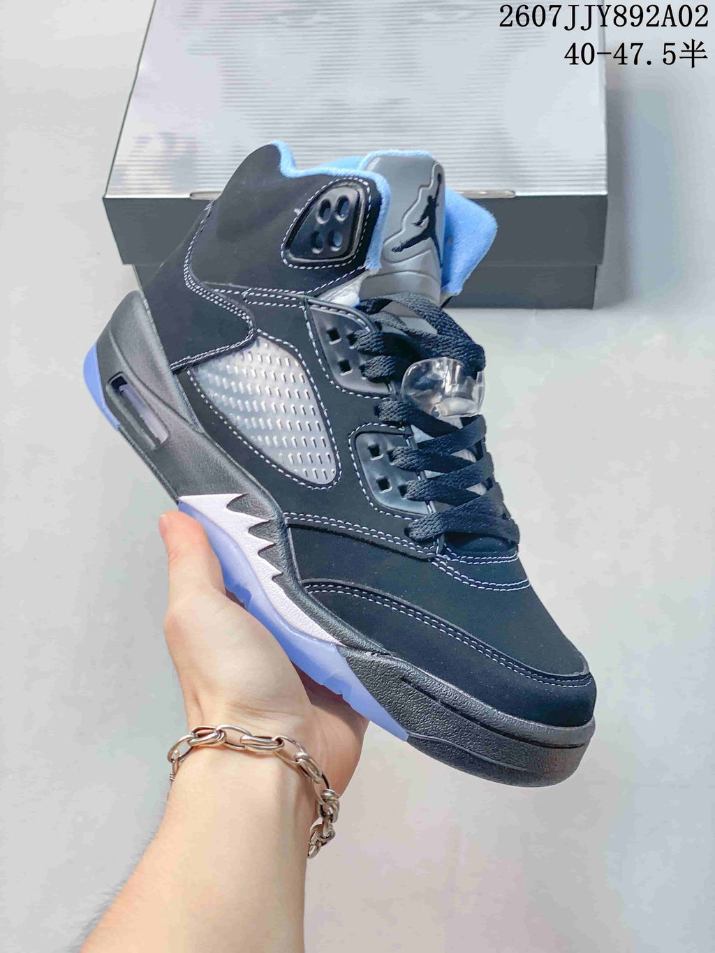 Angled side view of the dark sneaker with silver-toned details and blue outsole accents