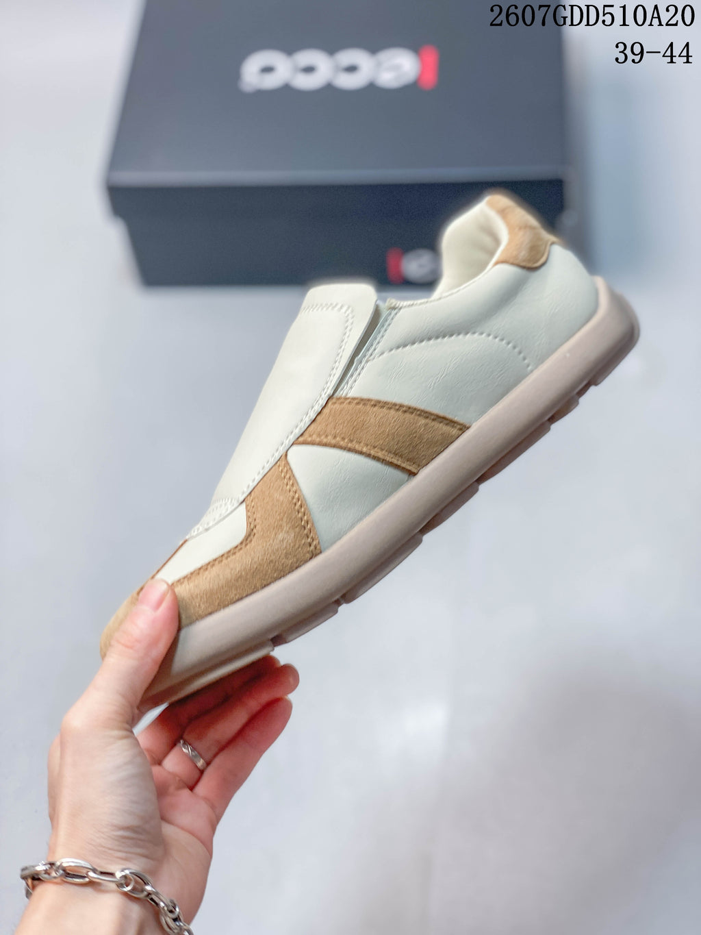 Side view showing the cream upper, tan contrast panels, and rounded sole.