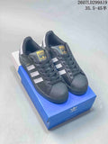 Pair of black adidas Superstar sneakers displayed on a blue shoebox, with white stripes and shell toes visible.