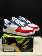Pair of white, blue, and red Bape Sta sneakers displayed on a branded camouflage shoe box.