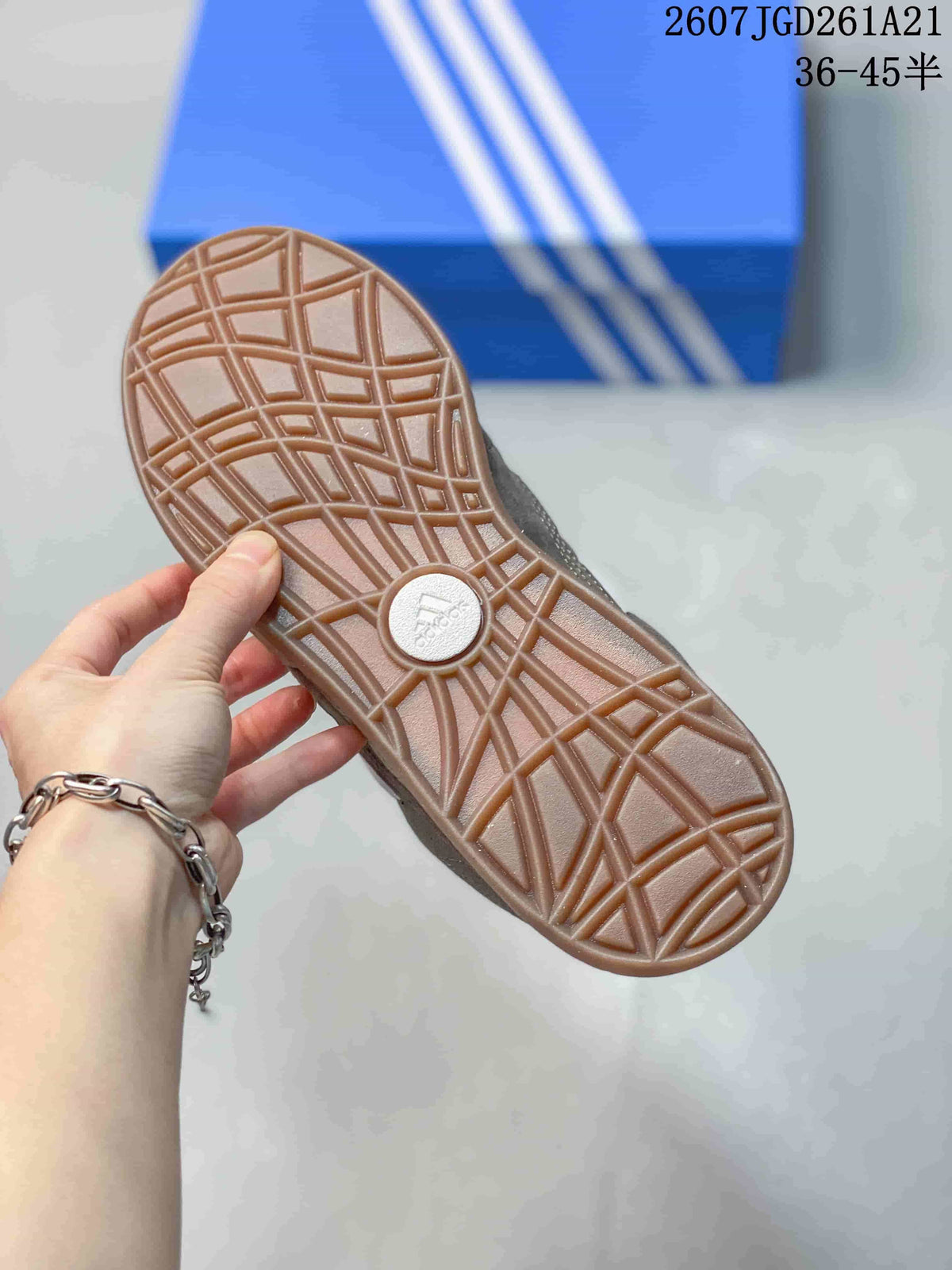 Close-up of the sneaker outsole showing a gum-colored geometric tread pattern and Adidas branding at the center.