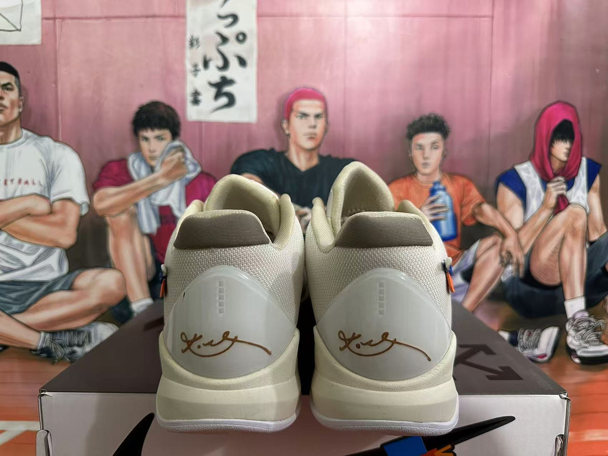 Rear view of pale cream basketball shoes showing heel signatures and a basketball-themed illustrated backdrop.