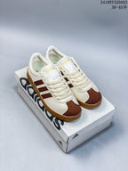 Pair of white and brown Adidas sneakers displayed on an Adidas shoe box.