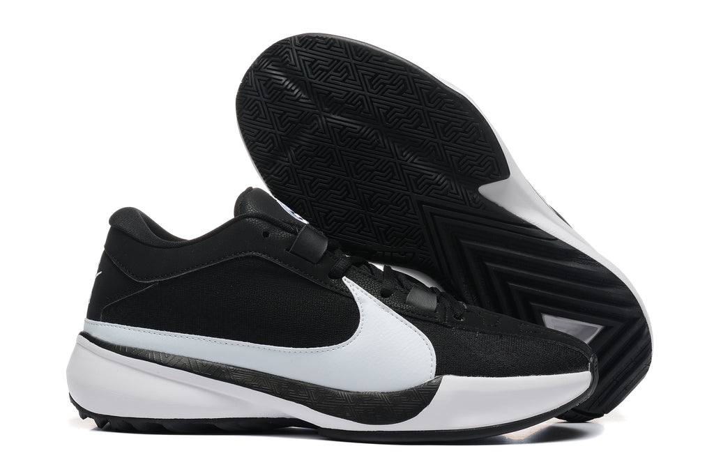 Black and white low-top basketball shoes shown with a close view of the patterned black outsole.