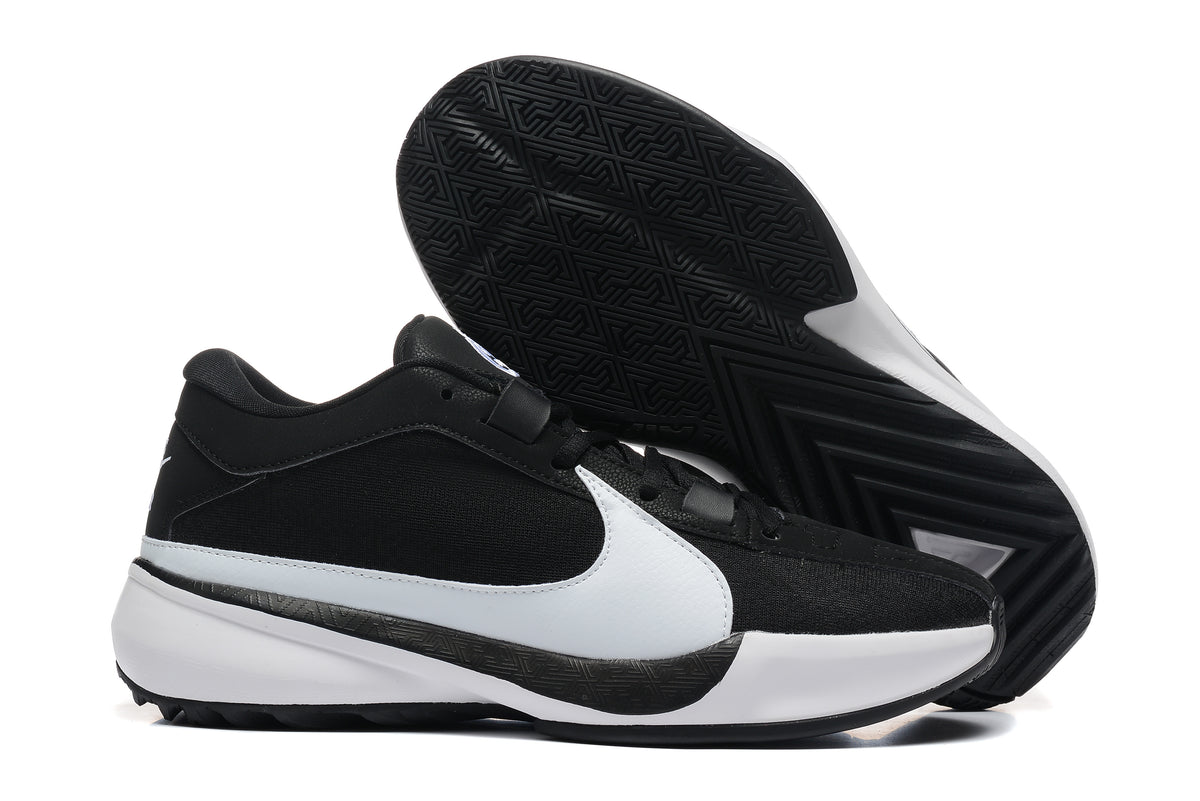 Black and white low-top basketball shoes shown with a close view of the patterned black outsole.