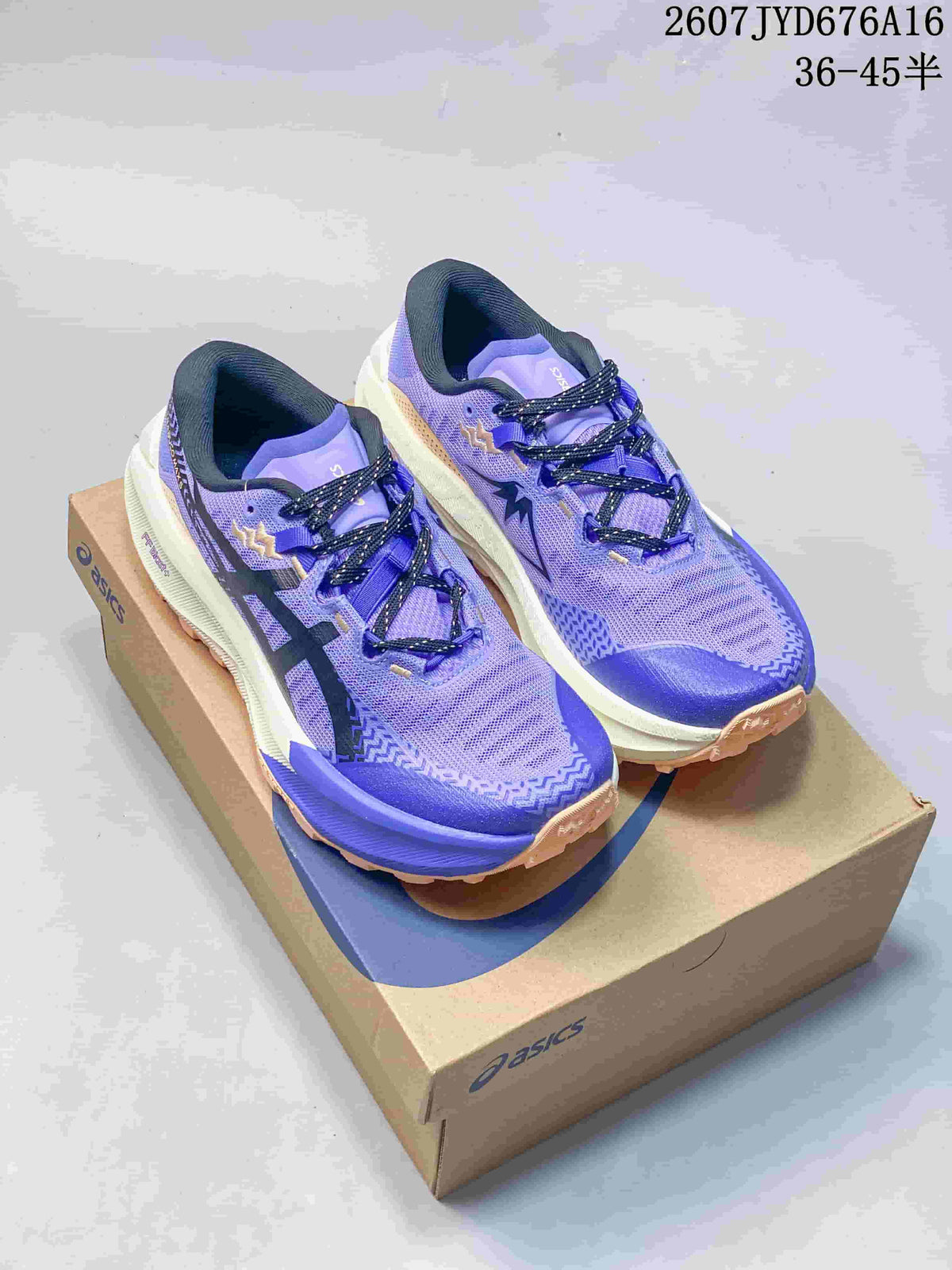 Pair of purple and blue ASICS Trabuco Max sneakers displayed on an ASICS shoebox.