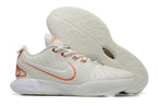 White Nike basketball shoe with orange trim and a pale outsole.