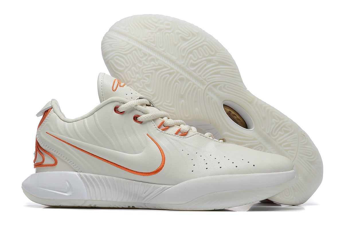 White Nike basketball shoe with orange trim and a pale outsole.