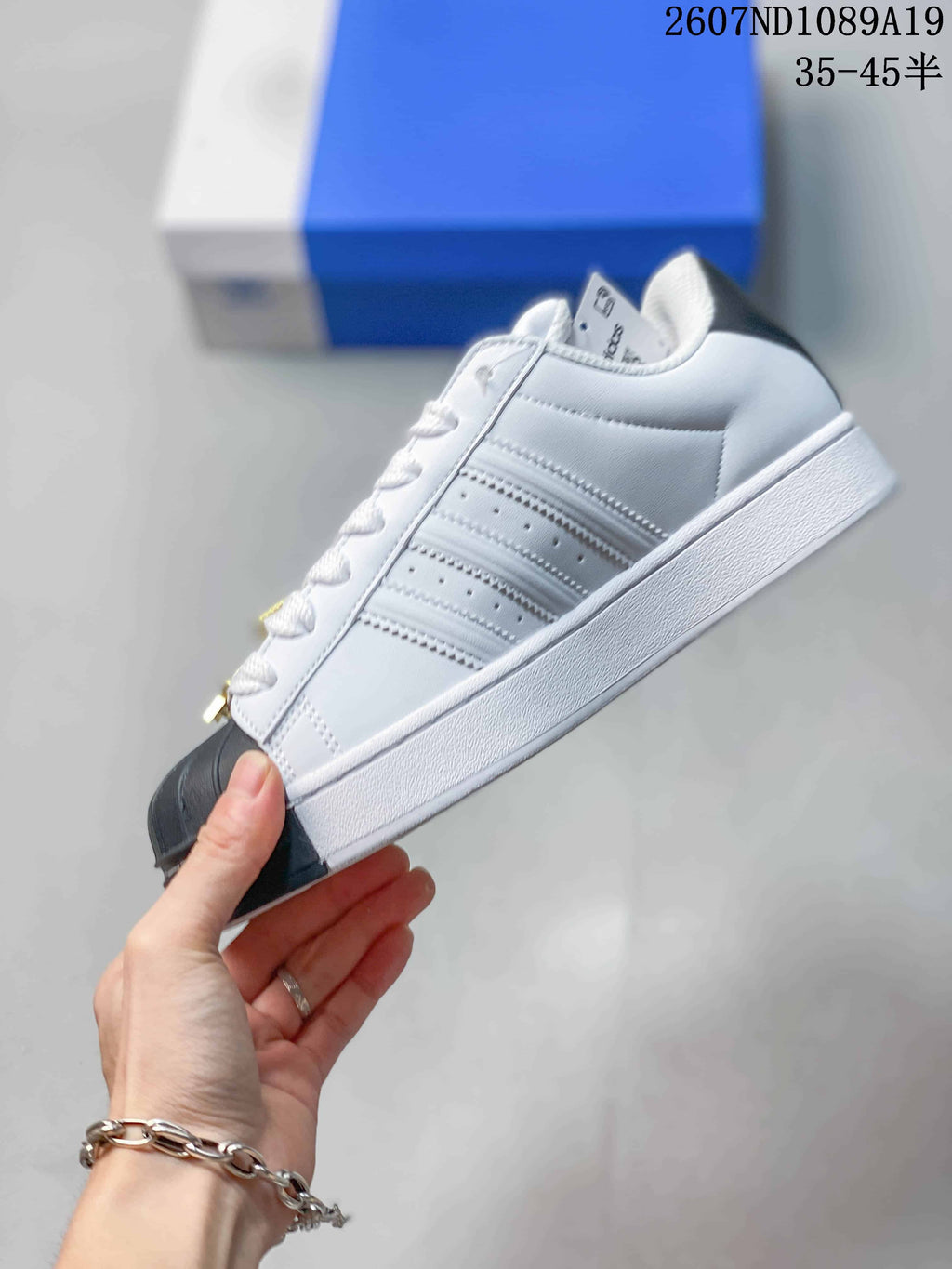 Side profile showing the white upper, layered three-stripe panels, black shell toe, and white platform-style sole.